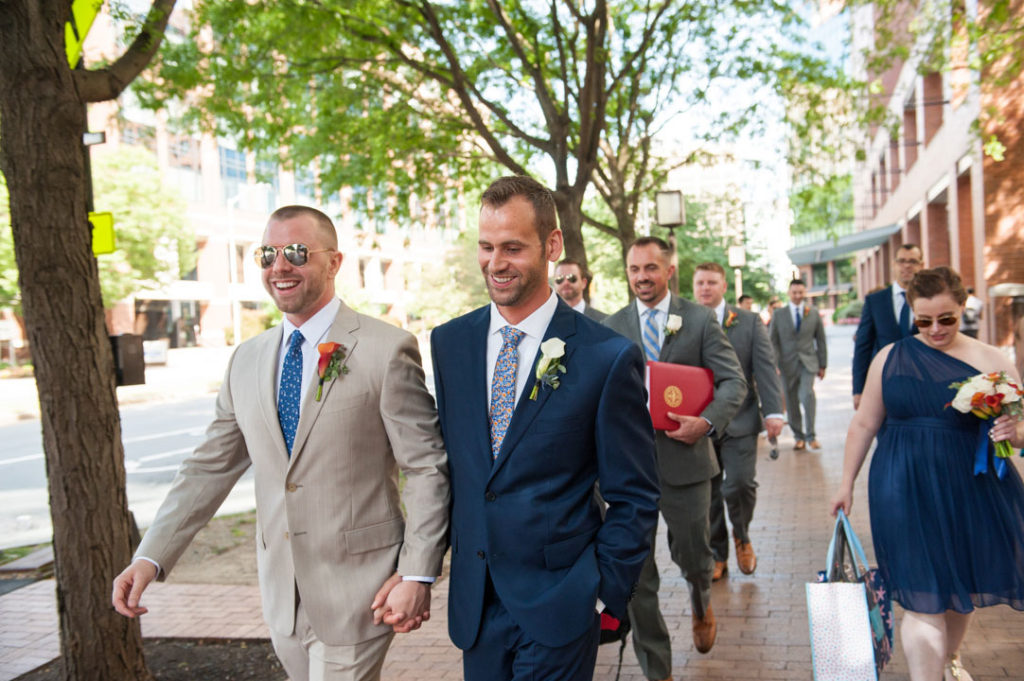 two grooms walk hand in hand to their wedding