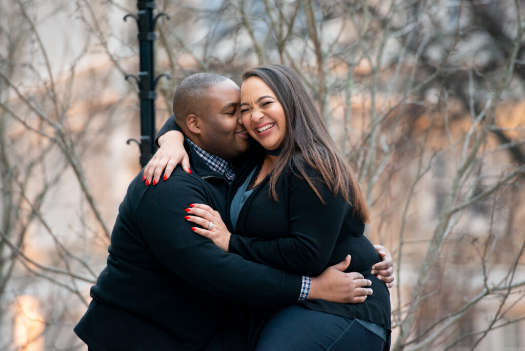 engagement photo at Boston College. couple is embracing; one person is saying something and the other person is laughing with their eyes closed