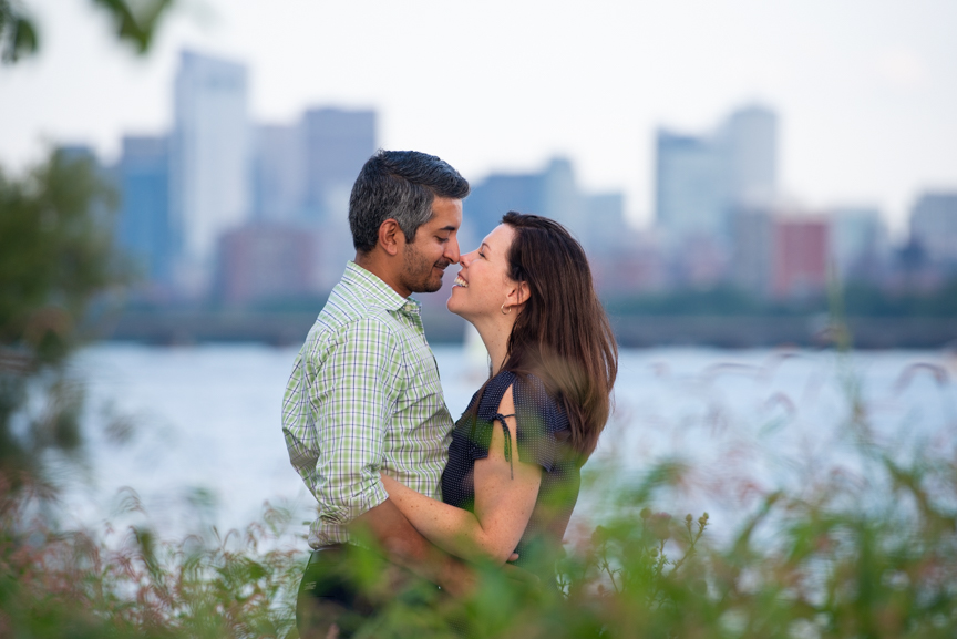 cambridge engagement photo couple almost kissing with Charles River and Boston skyline in the background