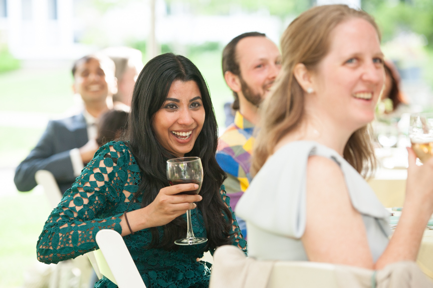 a wedding guest smiling and laughing while listening to a wedding toast