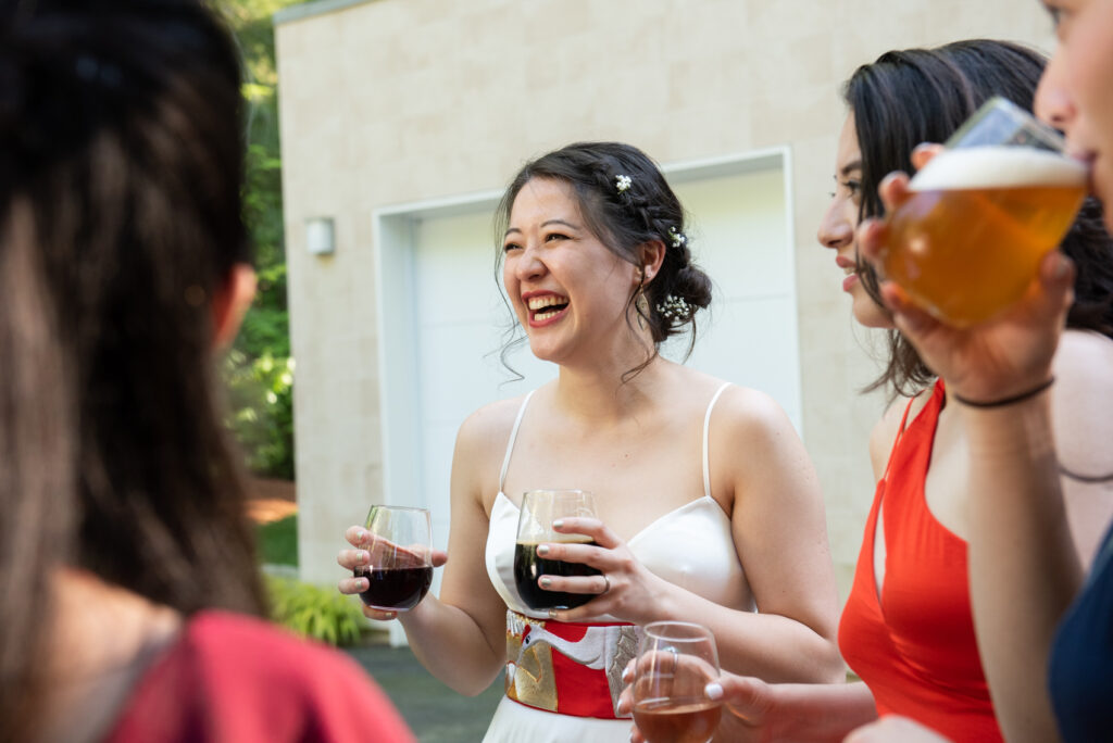 woman laughs candidly with her friends during her wedding reception at a backyard wedding in Lexington, Massachusetts