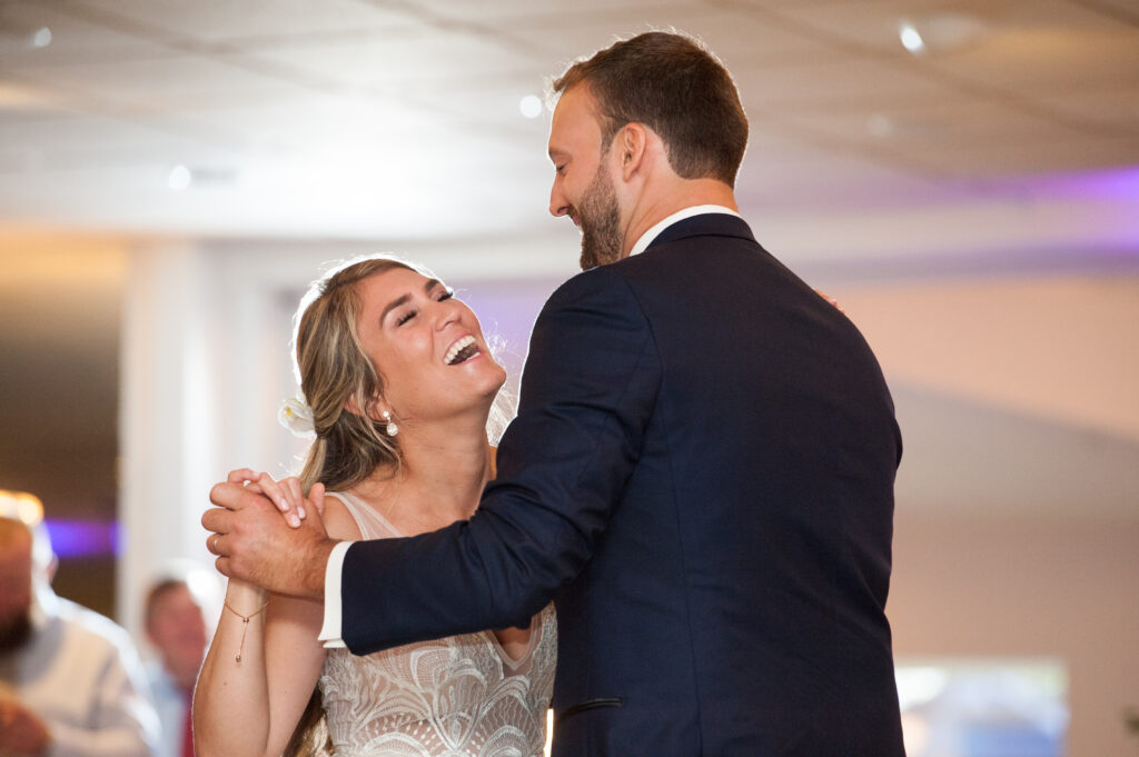 woman and man laughing while dancing at wedding