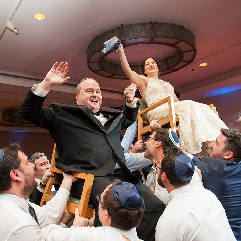 bride and groom dancing in lifted chairs